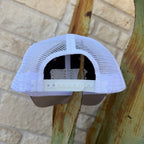 A white trucker-style cap viewed from the back, featuring a white mesh back and a white plastic snap closure