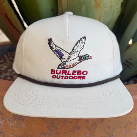A cream snapback cap featuring an embroidered flying duck logo and the text 'BURLEBO OUTDOORS' in red on the front, with a dark brown band around the crown.