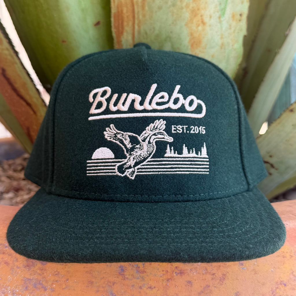 A dark forest green flat-brim cap with white embroidered text reading 'Burlebo' and a duck graphic with 'EST. 2015' on the front,