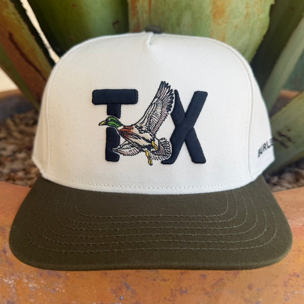 A white and olive green trucker-style cap featuring an embroidered 'TX' with a flying mallard duck in the center. 