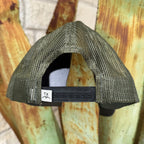 The back view of a trucker-style mesh cap in olive green, featuring a black adjustable strap with a white 'TX' logo patch