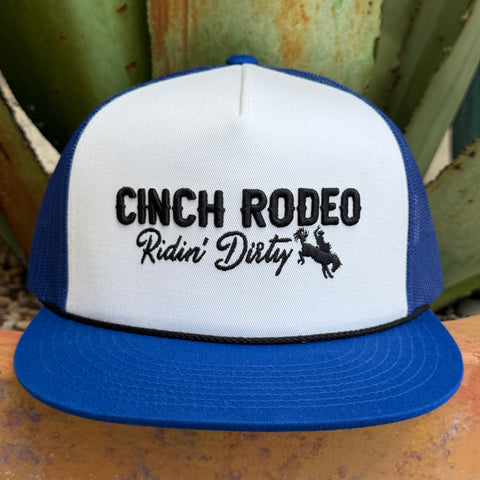 A blue and white trucker hat with black embroidered text reading 'CINCH RODEO Ridin' Dirty' and a cowboy riding a bucking horse