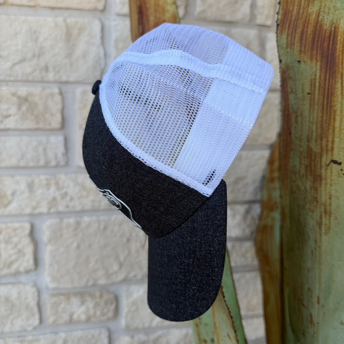 A black and white trucker-style cap with a black curved brim and white mesh back panels,