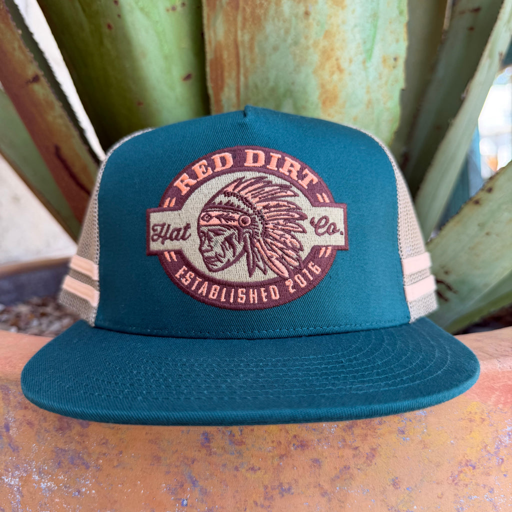 A teal and beige trucker hat with a front patch reading 'RED DIRT Flat Co. ESTABLISHED 2016' and featuring a Native American headdress graphic, 