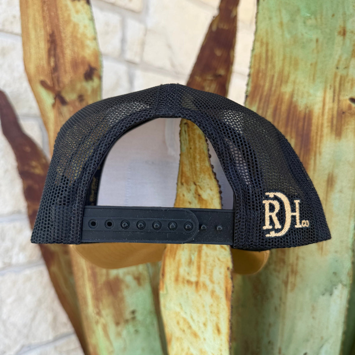 Black mesh trucker cap with an adjustable snapback strap and a gold embroidered 'RDH Co.' logo on the side