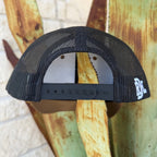 Black mesh trucker hat shown from the back, featuring a black adjustable strap and a white embroidered logo on the side that says "RDH" 