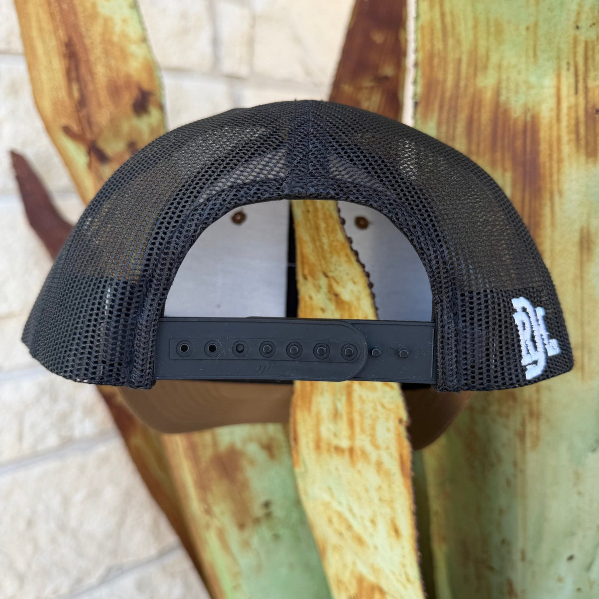 Black mesh trucker hat shown from the back, featuring a black adjustable strap and a white embroidered logo on the side that says "RDH" 