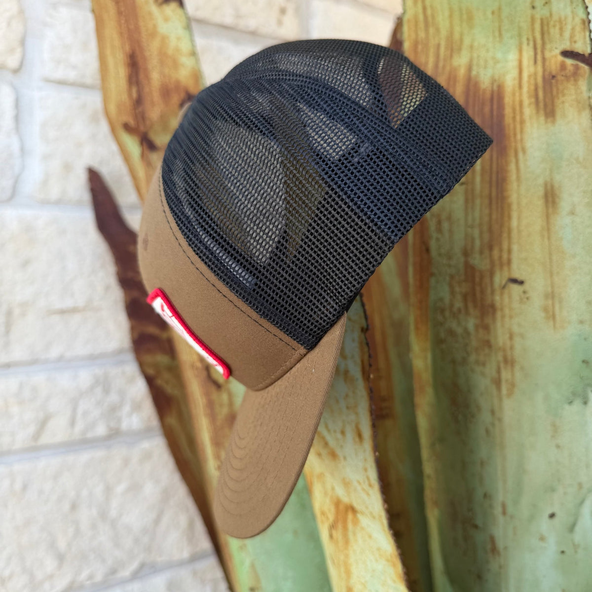 A tan and black trucker-style cap with a black mesh back,