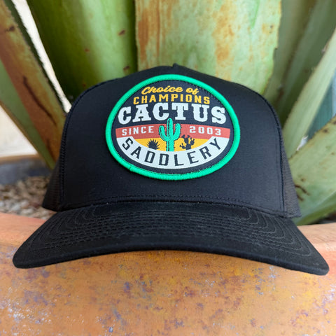 A black trucker-style cap with a circular embroidered patch reading 'Choice of Champions Cactus Saddlery Since 2003,' 