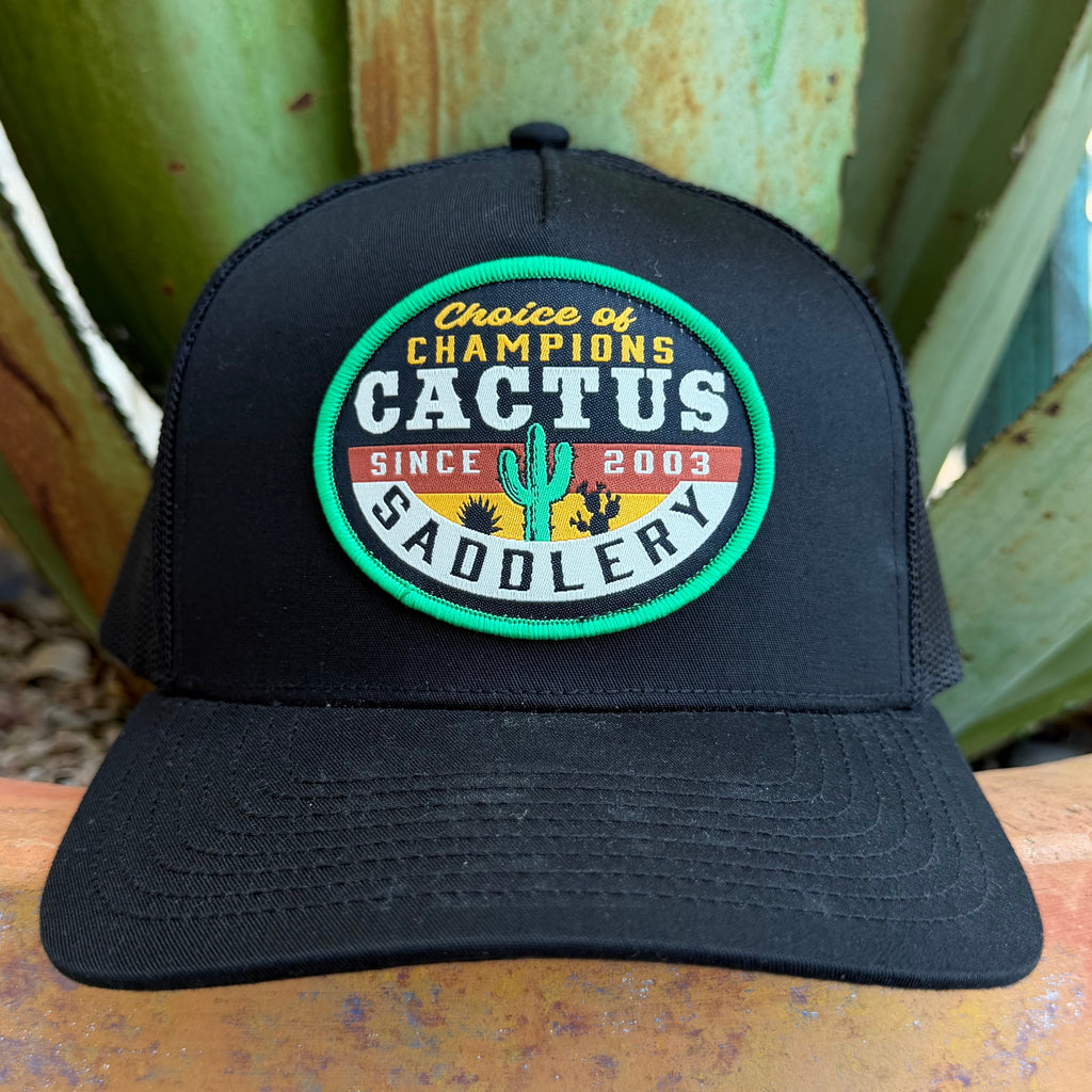 A black trucker-style cap with a circular embroidered patch reading 'Choice of Champions Cactus Saddlery Since 2003,