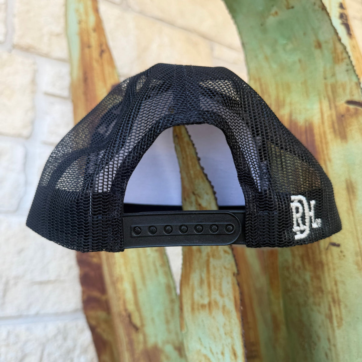 A black mesh trucker-style cap with an adjustable snapback closure and a white embroidered 'RDH' logo on the side