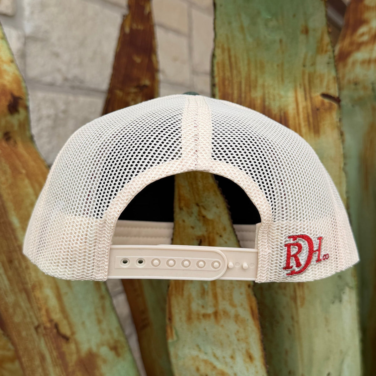 An off-white mesh trucker cap shown from the back, featuring a red embroidered 'RDH' logo on the side
