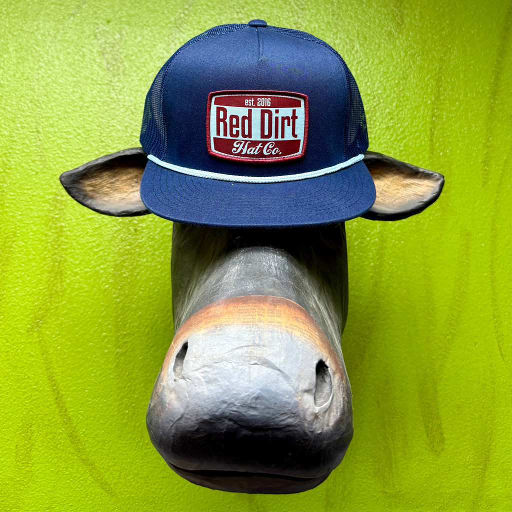 Men’s Red Dirt Hat Co. mesh snapback cap in navy with maroon patch, breathable mesh back, and light blue rope trim – RDHC433. Available at Blair’s Western Wear, Marble Falls, TX.