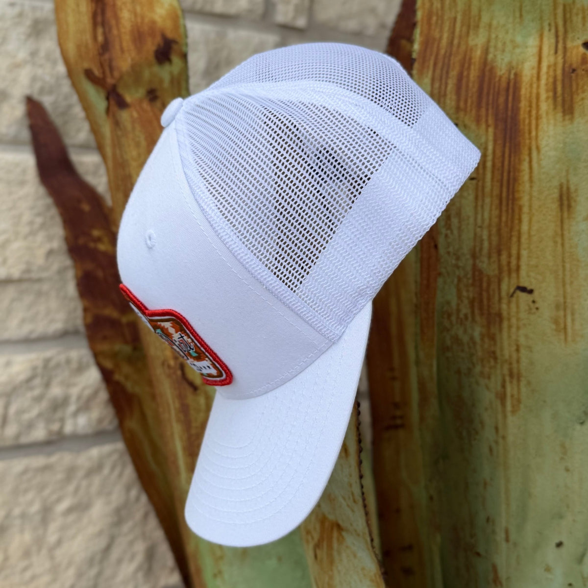 Men's White cap with aztec Red Dirt Hat Co. Logo at the front in the colors red-orange, brown , and turquoise  - it has a an adjustable snapback strap on the back for adjustable fit 