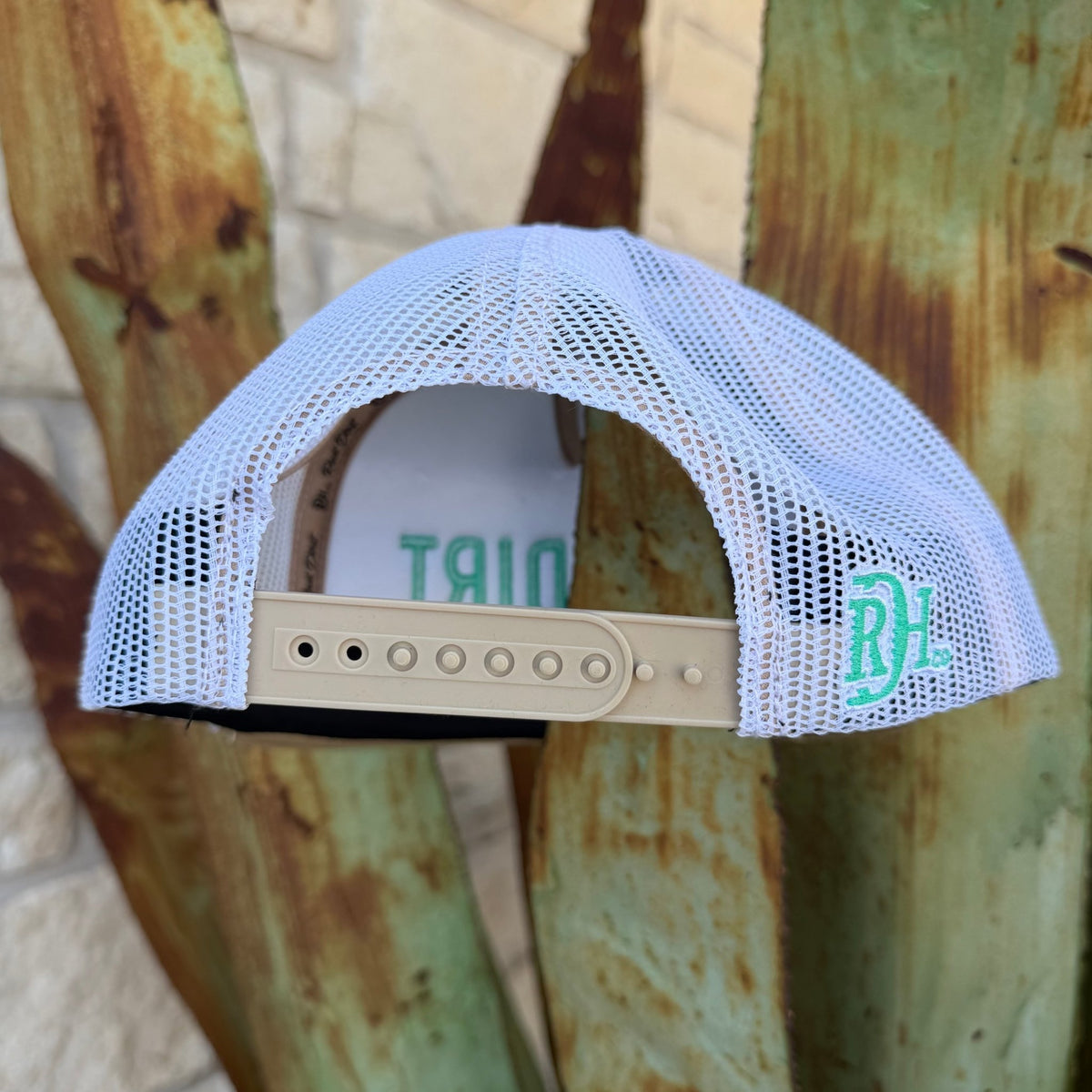 A white mesh back trucker hat shown from the back,The hat features a beige adjustable strap and a mint green circular 'RDH' logo on the side.