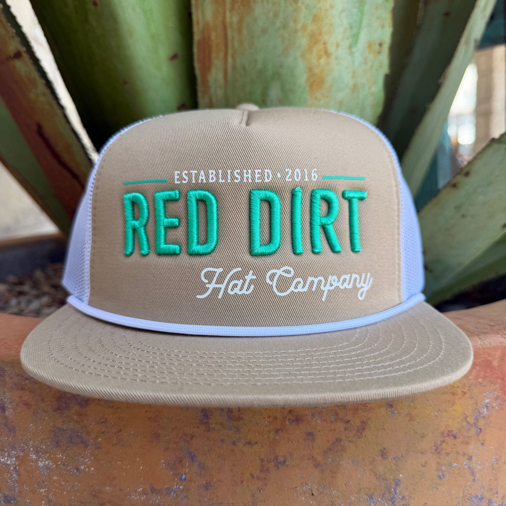 A beige trucker hat with turquoise and white embroidered text reading 'RED DIRT Hat Company' and 'ESTABLISHED 2016', 
