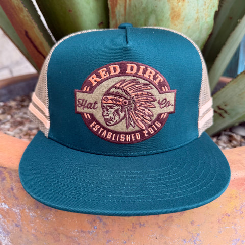 A teal and beige trucker hat with a circular embroidered front patch reading 'Red Dirt Hat Co. Established 2016' and showing a Native American headdress graphic