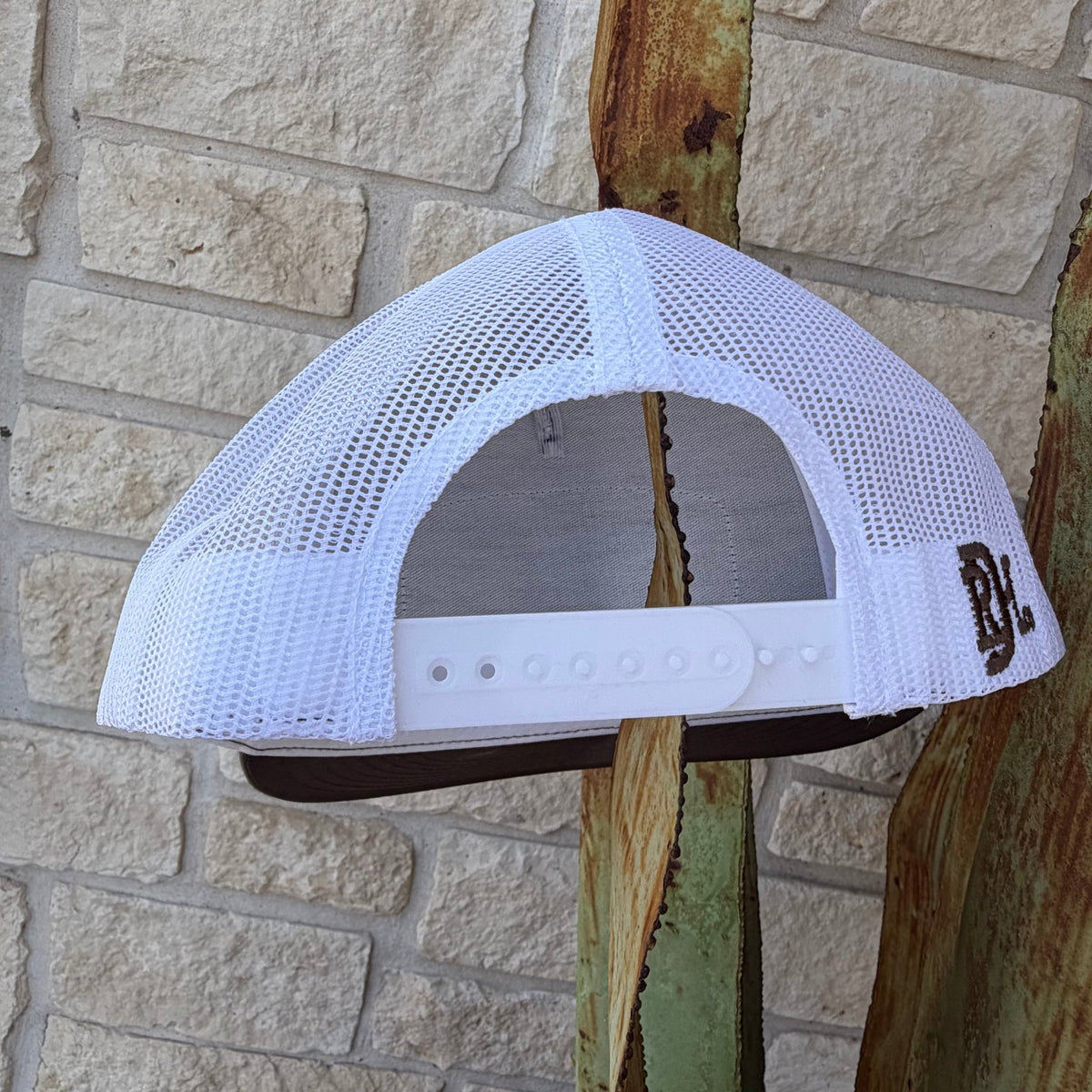 White mesh trucker cap shown from the back, featuring a white adjustable strap and a brown embroidered 'RDH' logo on the side,