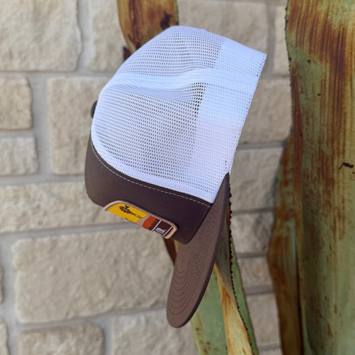 A brown and white trucker-style cap with a white mesh back and brown visor