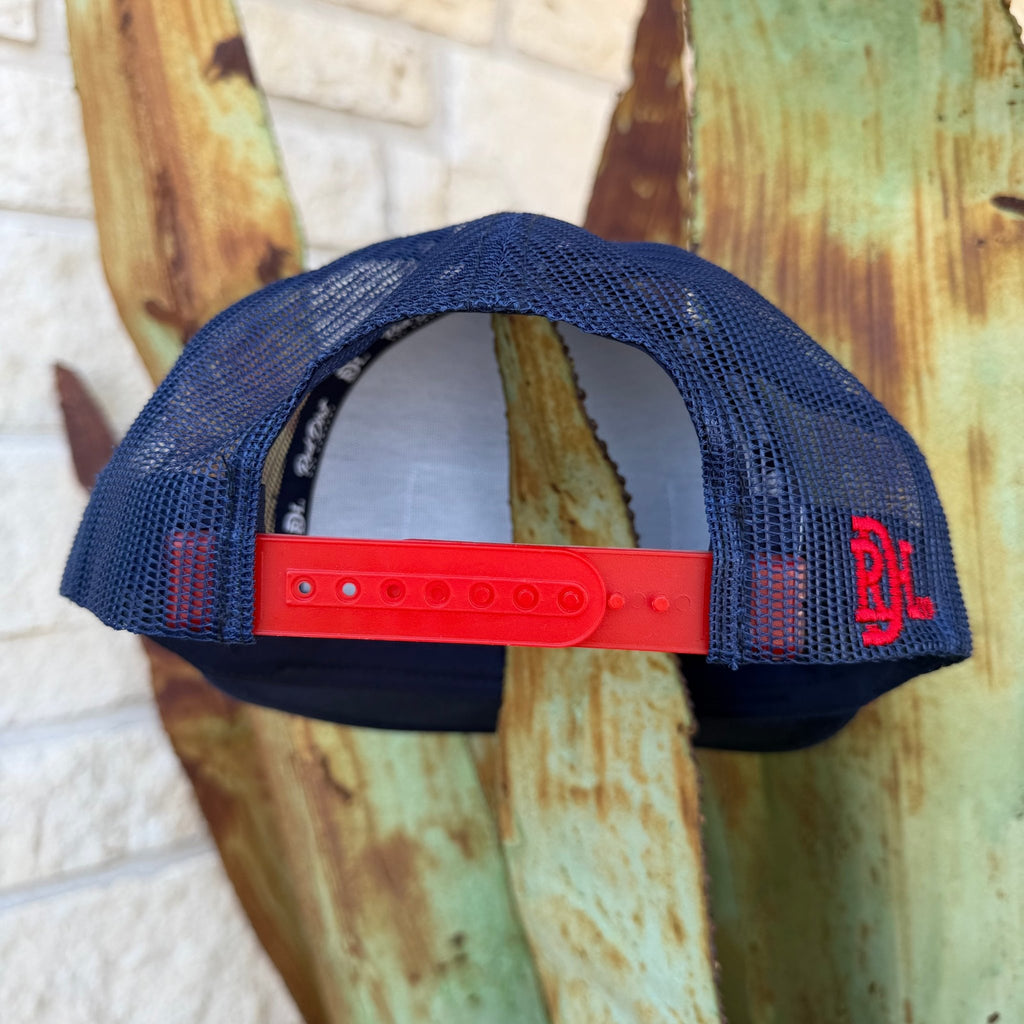 This Red Dirt Hat Co. trucker keeps it classic with a structured navy front, breathable mesh back, and a bold embroidered patch that does all the talking. The red rope accent cord along the brim adds just enough detail to set it apart from every other cap on the rack.