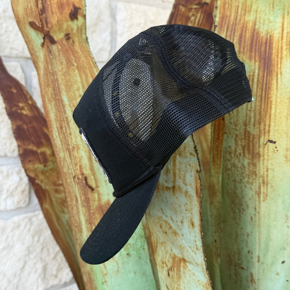 A black trucker-style cap with a black mesh back and curved brim, 
