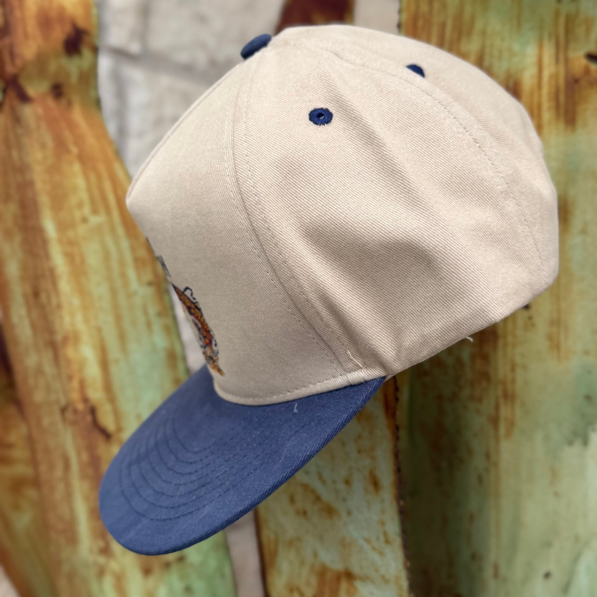 A cap with an off-white crown and a blue visor,