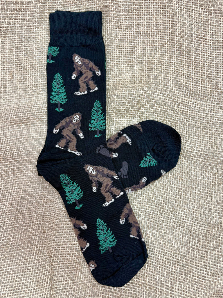 Men's Socksmith novelty crew socks in black, made with a breathable cotton blend, featuring a Bigfoot and tree design, with reinforced heel and toe for durability - SSM1423B. Available at Blair's Western Wear, Marble Falls, TX.