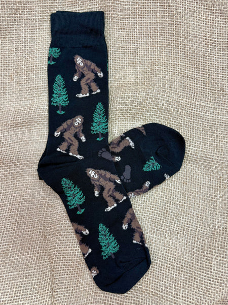 Men's Socksmith novelty crew socks in black, made with a breathable cotton blend, featuring a Bigfoot and tree design, with reinforced heel and toe for durability - SSM1423B. Available at Blair's Western Wear, Marble Falls, TX.