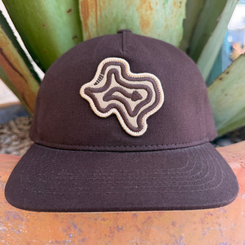 A dark brown cap with a topographic-style embroidered logo patch on the front