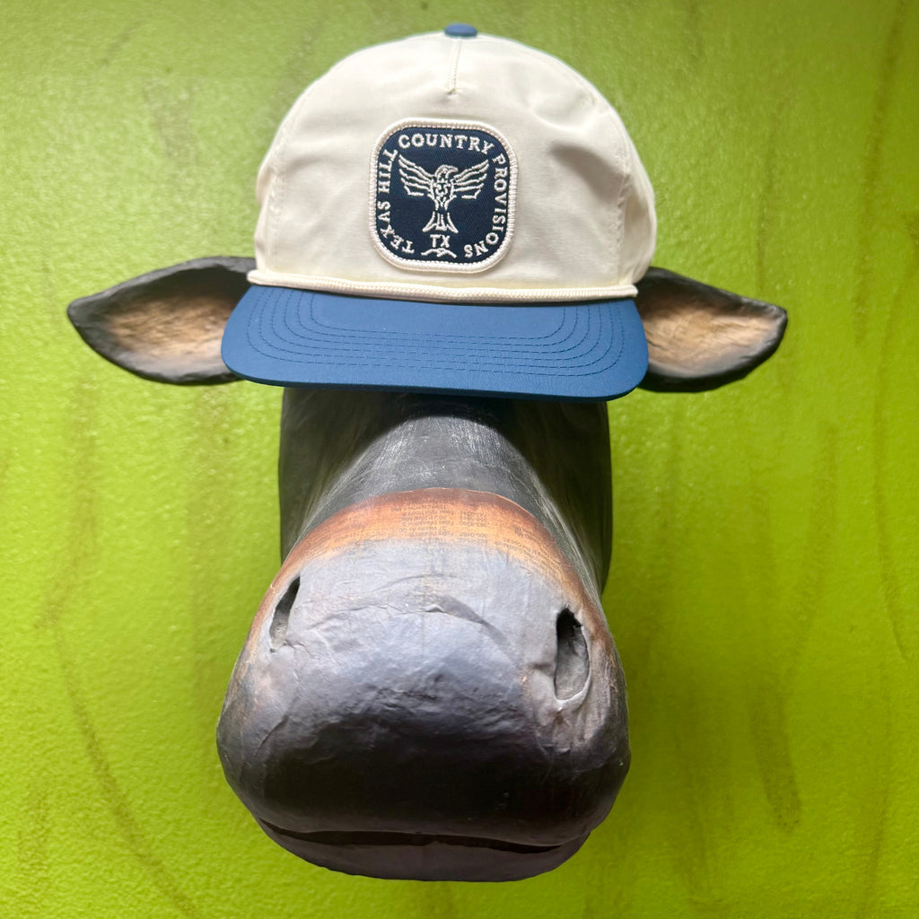 Men’s THC Provisions Trucker Cap in Natural/Navy, featuring the Higher Calling Thunderbird patch, with sweat-wicking mesh back, UPF 40+ sun protection, and an adjustable snapback for all-day comfort - HIGHER CALL NV. Available at Blair's Western Wear, Marble Falls, TX.