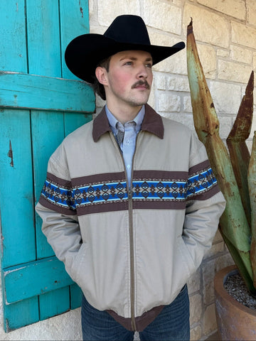 Men’s Wrangler cotton canvas jacket in tan with brown collar and blue Aztec embroidery, featuring quilted lining and rib-knit cuffs – 112368287. Available at Blair’s Western Wear, Marble Falls, TX.