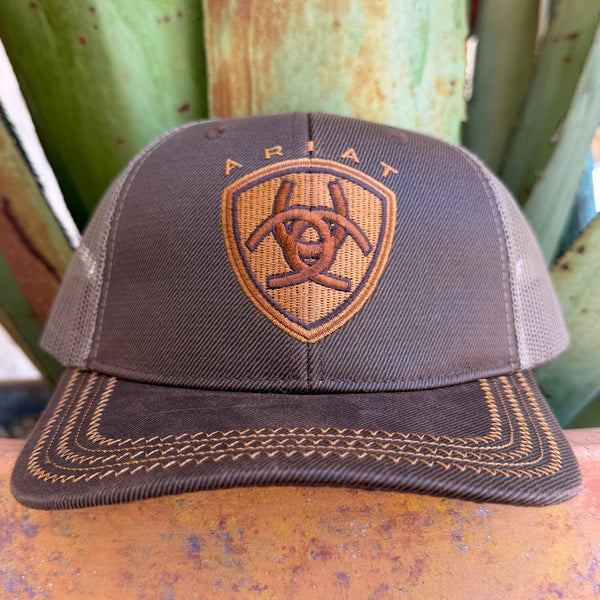 A brown mesh-back trucker hat with an embroidered Ariat shield logo on the front, 