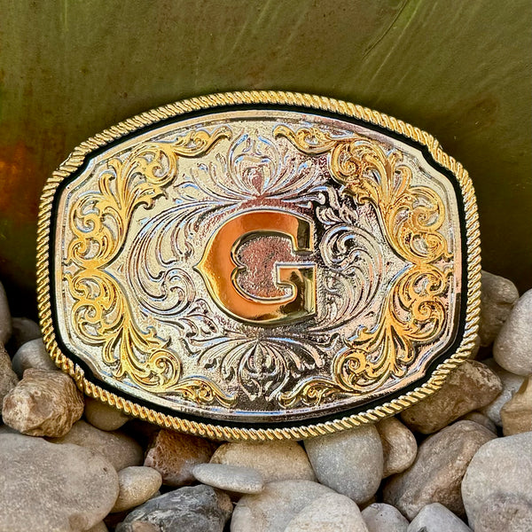 Montana Silversmiths Belt Buckle in silver and gold, featuring detailed engravings and filigree embellishments with a central gold initial - A1047G. Available at Blair's Western Wear, Marble Falls, TX.