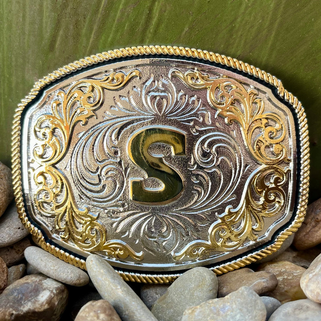 Montana Silversmiths Belt Buckle in silver and gold, featuring detailed engravings and filigree embellishments with a central gold initial - A1047S. Available at Blair's Western Wear, Marble Falls, TX.