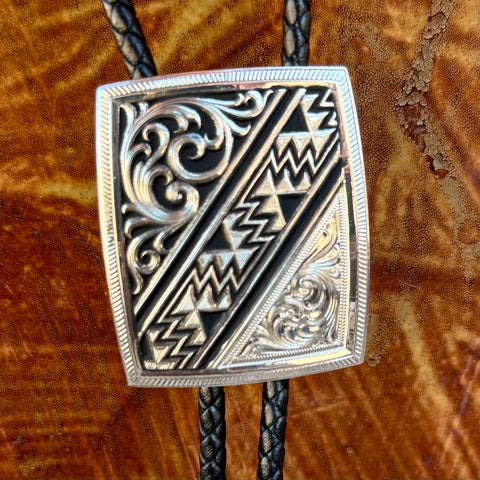 Montana Silversmiths Bolo Tie Silver Aztec in silver, engraved silver-tone pendant with bold Aztec-inspired geometric detailing, with black braided leather cord for durable all-day wear - BT6064. Available at Blair's Western Wear, Marble Falls, TX.