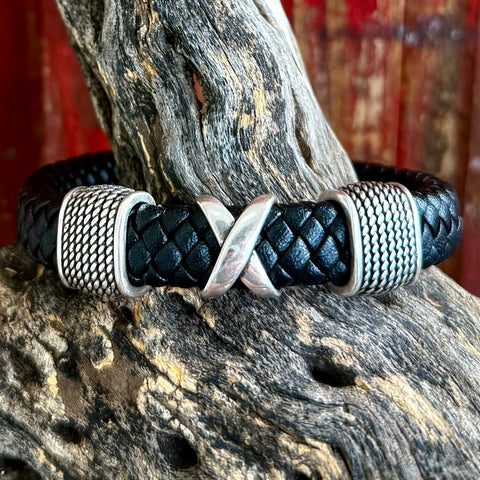 Montana Silversmiths braided leather bracelet in black with a silver “X” centerpiece and textured silver accents, featuring a secure magnetic clasp – BC5381. Available at Blair's Western Wear, Marble Falls, TX.