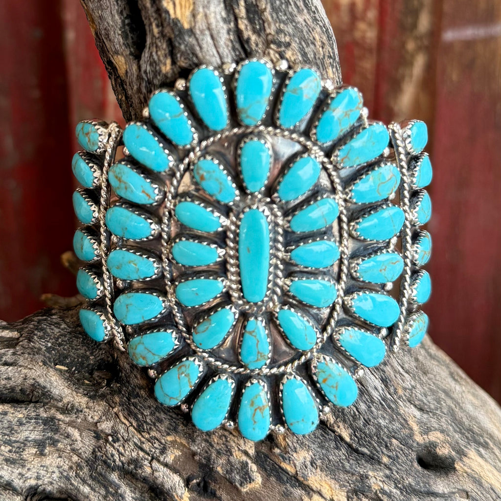 Nizhoni Traders bracelet turquoise cuff bracelet in blue, crafted from genuine turquoise stones arranged in a bold cluster design, with hand-set sterling silver bezels highlighting traditional Southwestern craftsmanship - NZCUFFTQ. Available at Blair's Western Wear, Marble Falls, TX.
