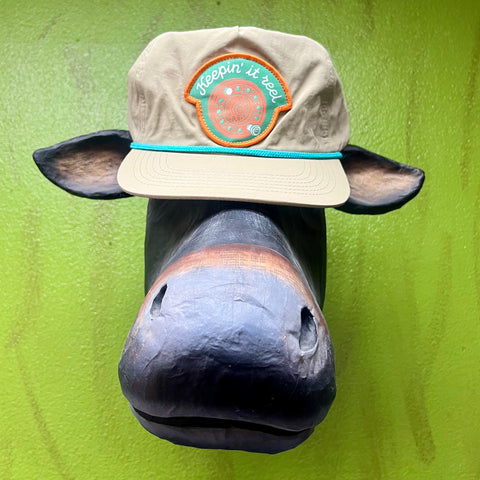 Sendero cap hat in tan, flat brim with turquoise rope detail, with embroidered “Keepin’ it reel” patch in orange and teal - KEEP REEL. Available at Blair's Western Wear, Marble Falls, TX.