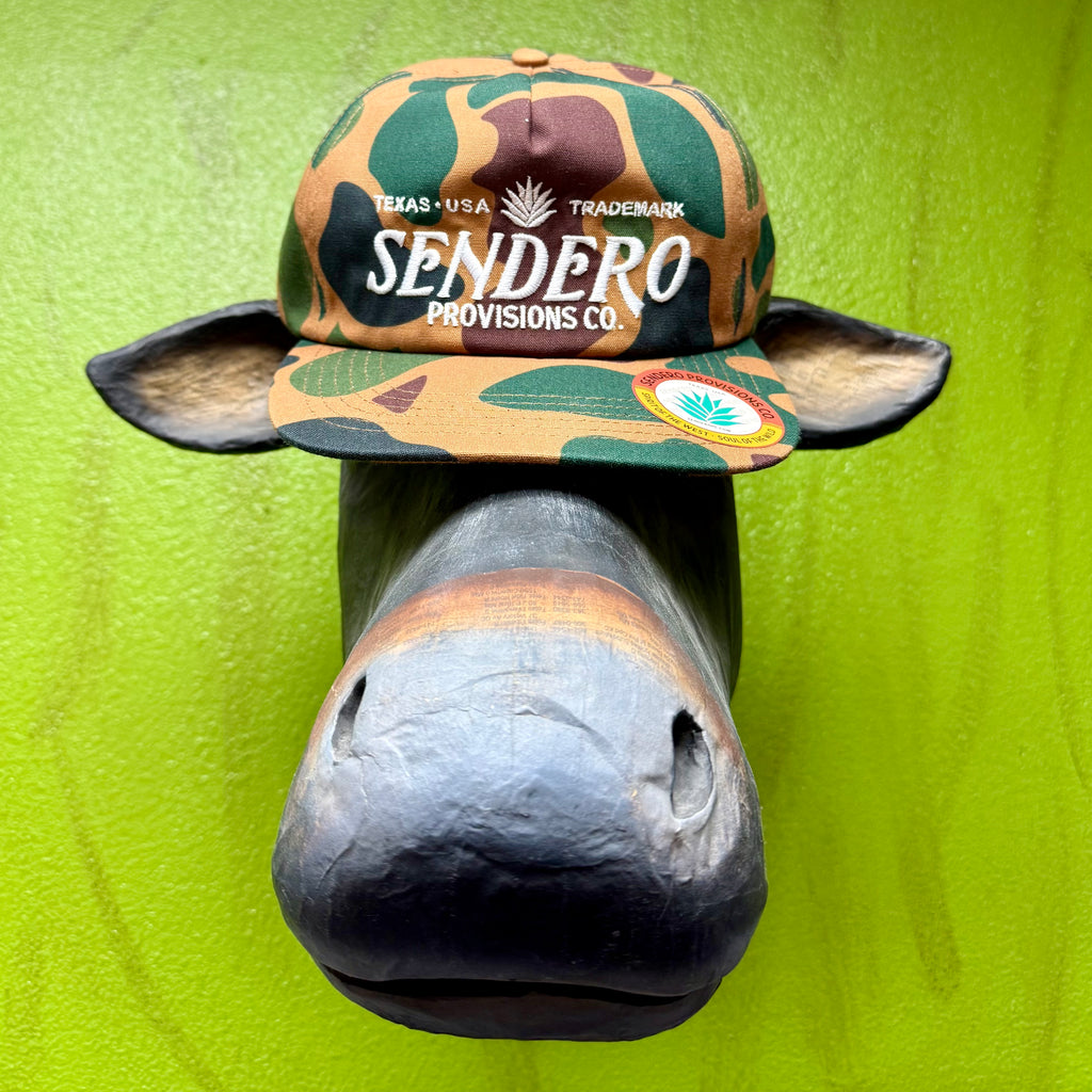 Sendero Provisions Co. camo logo hat in field camo, featuring an embroidered front logo and an adjustable snapback closure for a customized fit – CAMO LOGO. Available at Blair's Western Wear, Marble Falls, TX.