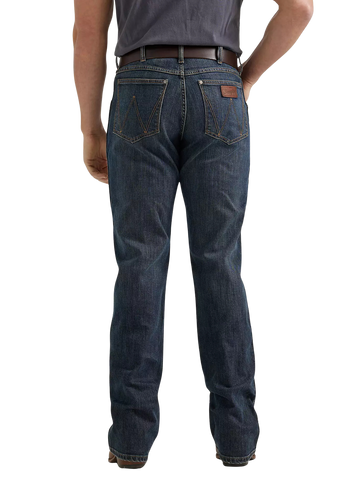 Rear view of a person wearing dark blue denim jeans with a brown leather patch on the back pocket, paired with a dark gray t-shirt and brown belt, against a plain white background.