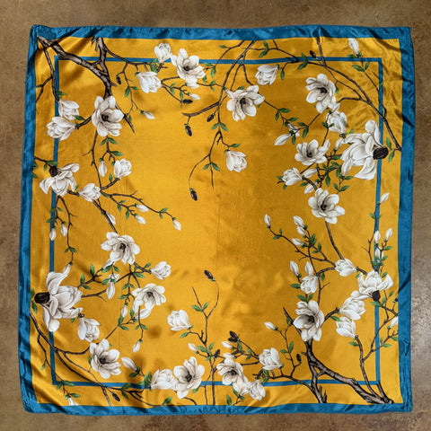 Women's Floral Wild Rag in mustard yellow with teal border, lightweight satin fabric with magnolia floral print, and versatile square shape - Available at Blair's Western Wear, Marble Falls, TX.