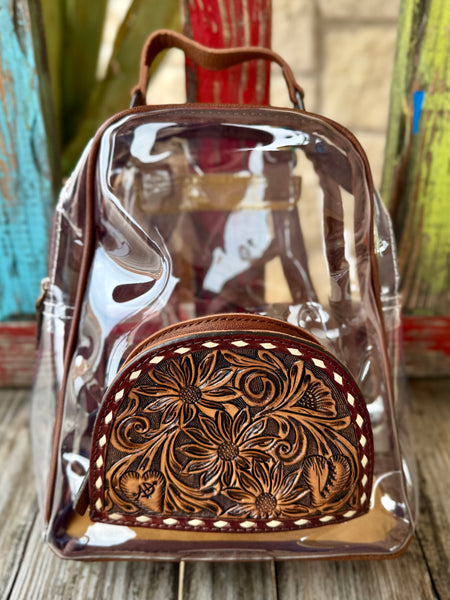 Women’s American Darling clear backpack with brown hand-tooled leather front pocket, transparent PVC body for event compliance, and adjustable leather shoulder straps - ADBGS156AK. Available at Blair's Western Wear, Marble Falls, TX.