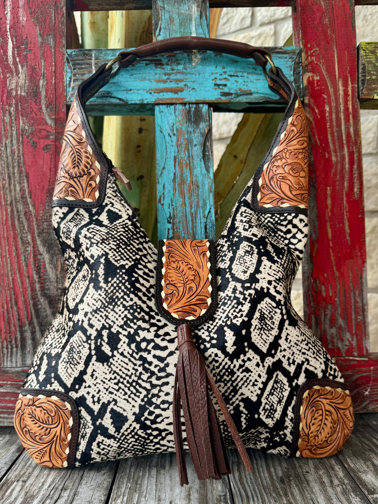 Women’s American Darling hobo bag in black and cream hide print, crafted from genuine leather with tooled leather corner accents, with exterior zip pockets for organized storage - ADBGA237F. Available at Blair's Western Wear, Marble Falls, TX.