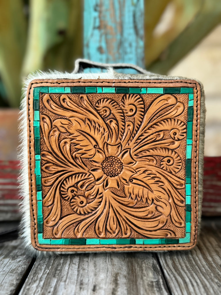 Women’s American Darling jewelry case in tan and turquoise hair-on cowhide, with hand-tooled floral leather overlay and zip-around closure, featuring interior compartments and soft velvet lining — ADBGA311D. Available at Blair’s Western Wear, Marble Falls, TX.