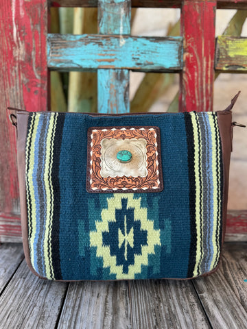 Women’s American Darling saddle-blanket messenger bag in brown and navy, featuring tooled leather concho and adjustable tooled strap, with organizational interior pockets — ADBGA286H. Available at Blair’s Western Wear, Marble Falls, TX.