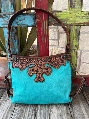 Women’s American Darling stud tool hide purse in turquoise hair-on hide and brown leather, featuring hand-tooled floral overlays and antique stud accents with adjustable leather strap – ADBG713H. Available at Blair's Western Wear, Marble Falls, TX.