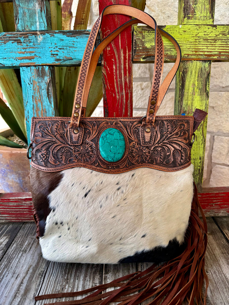 Women’s American Darling Western crossbody hide bag in brown, crafted from genuine hair-on cowhide with hand-tooled leather detailing, featuring a turquoise-tone stone accent and adjustable leather strap - ADBGS144BRWBRSTO. Available at Blair's Western Wear, Marble Falls, TX.