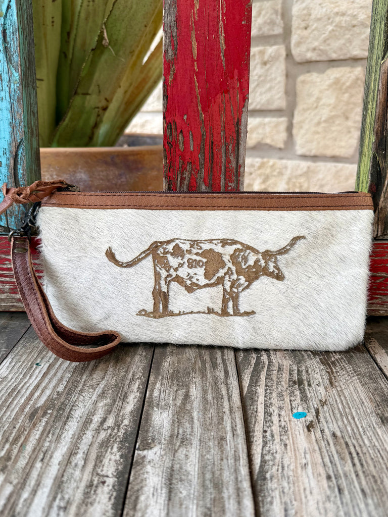 Women’s American Darling wristlet hide longhorn in natural and brown, genuine hair-on hide construction with longhorn graphic and zip-top closure, featuring removable leather wrist strap – ADBG344BM. Available at Blair's Western Wear, Marble Falls, TX.