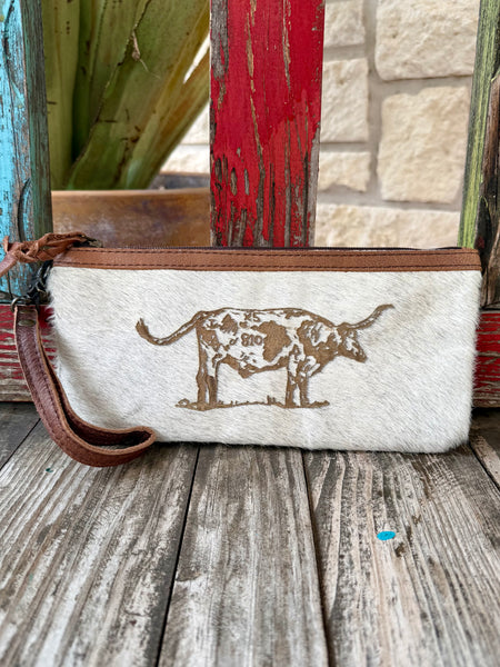 Women’s American Darling wristlet hide longhorn in natural and brown, genuine hair-on hide construction with longhorn graphic and zip-top closure, featuring removable leather wrist strap – ADBG344BM. Available at Blair's Western Wear, Marble Falls, TX.