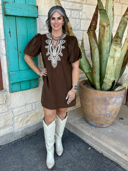 7418D — Women's chocolate brown fine wale corduroy mini shift dress with ornate ivory cream medallion embroidery at V-neckline, dramatic short puff sleeves gathered at shoulder cap, relaxed straight silhouette, and side seam pockets, styled with tall white western boots — Blair's Western Wear Marble Falls TX